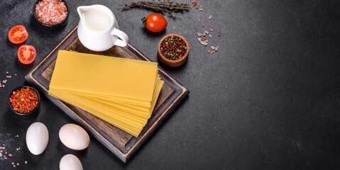 Stack of lasagna sheets on a dark concrete background. Ingredients for lasagna