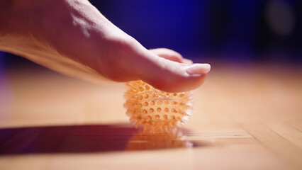 Person feet pick up spike massage ball from the floor with toes side view - obrazy, fototapety, plakaty