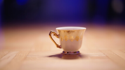 Gold teacup on floor under spotlight in moody light