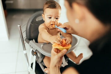 Mother feeding child. First solid food for children. Baby weaning