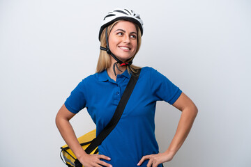 Young caucasian woman with thermal backpack isolated on white background posing with arms at hip and smiling