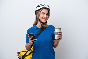 Young caucasian woman with thermal backpack isolated on white background holding coffee to take away and a mobile