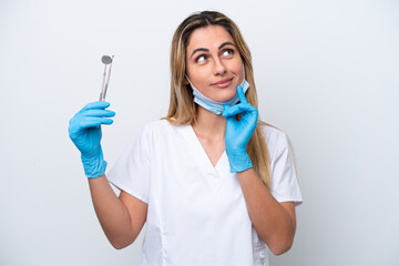 Dentist woman holding tools isolated on white background thinking an idea while looking up