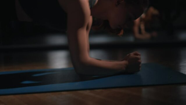 Young woman exercises arms with commandos on the floor, slow motion