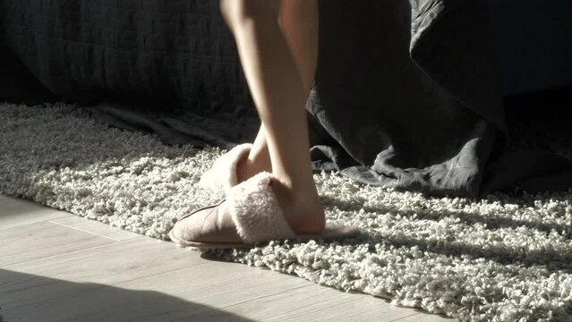 Person puts on cozy warm slippers in early winter morning, motion view