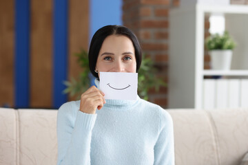 Woman holds painted smile for on piece of paper closeup