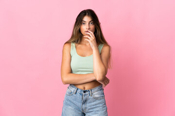 Young caucasian woman isolated on pink background surprised and shocked while looking right