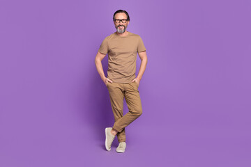 Fototapeta na wymiar Full length photo of mature cheerful man hands in pocket wear modern clothes isolated over violet color background