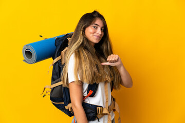 Young mountaineer woman with a big backpack isolated on yellow background proud and self-satisfied