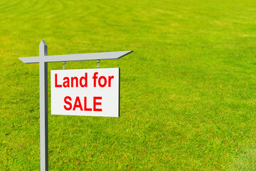 Land for sale sign. Illustration on theme of real estate. Purchase of a land plot. White sign for sale on a lawn background. Concept - Plot of land for sale by a realtor. Realtor business.