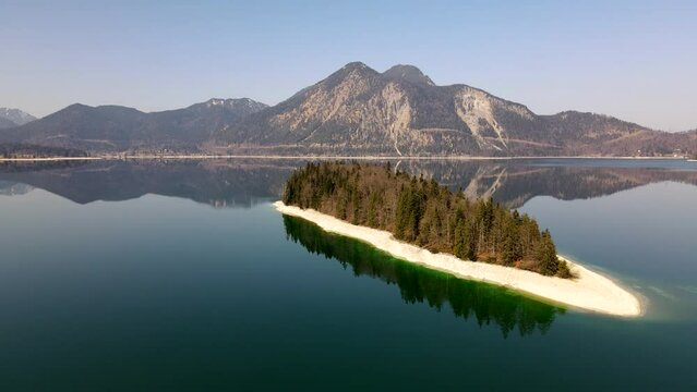 Aerial drone of Island of Sassau in Lake Walchen, Walchensee in Bavaria Germany, with Herzogstand mountain in spring in 4k, HD und UHD