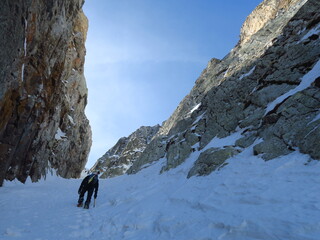 Fototapeta na wymiar ski de rando et alpinisme dans un couloir de glace en montagne avec piolet et crampons et casque pour escalader en hiver dans la neige