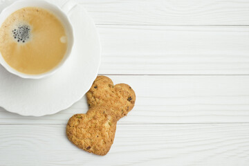Homemade cakes for breakfast and coffee in a white porcelain cup. Shortbread cookies in the shape of a heart on a white saucer. Background for design, space for text