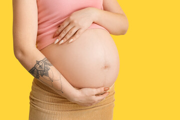 Pregnant young woman on yellow background
