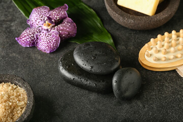 Wet spa stones with sea salt and massage brush on dark background