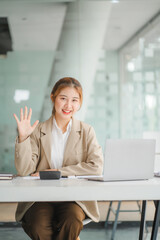 Portraits of beautiful smiling Asian women relax using laptop computer technology while sitting on their desks and using their creativity to work, work from home concept.