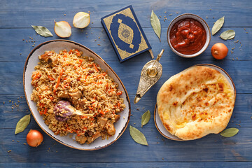 Plate of traditional pilaf with flatbread, Quran and Aladdin lamp on table