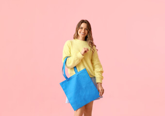 Pretty young woman with blue eco bag on pink background