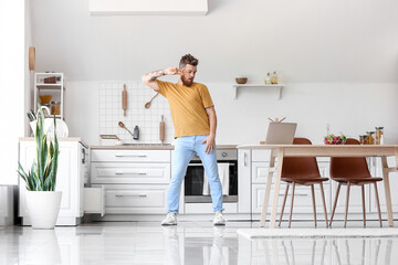 Cool young man with laptop learning to dance at home