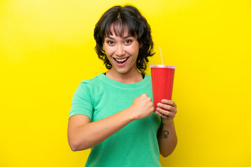Young Argentinian woman holding a soda isolated on yellow background celebrating a victory