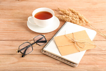 Composition with eyeglasses, cup of tea and card on wooden background