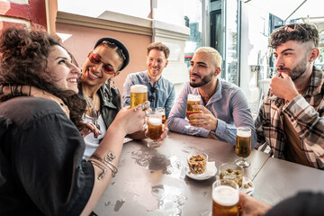 Group of friends drinking beer at brewery bar and talking, smiling. Young millenial students having fun together.