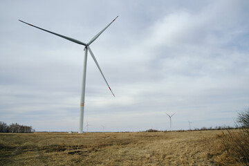 Wind turbines on a field with yellow grass and against a cloudy sky.Environmentally friendly renewable energy.