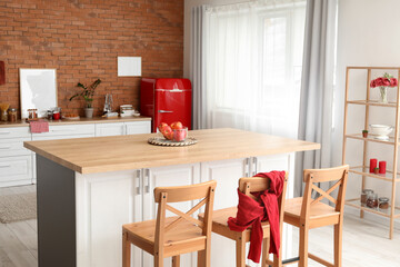 Interior of modern kitchen with dining table, counter and stylish refrigerator