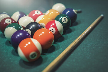 billiard cue and a pyramid of colorful balls on a green pool table.