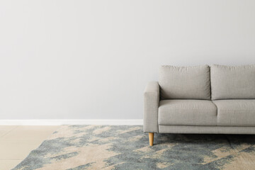 Fototapeta na wymiar New grey sofa near light wall