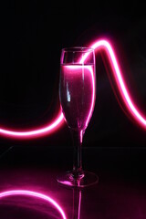 Lìneas curvas bordean la copa de champàn de cristal con luz de neòn color rosa, produce por reflexiòn un hermoso y delicado dibujo abstracto para fondos de diseño con fondo negro