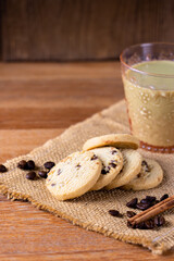 Coffee cookie and glass of almon green tea milk on wooden table decorated with coffee beans