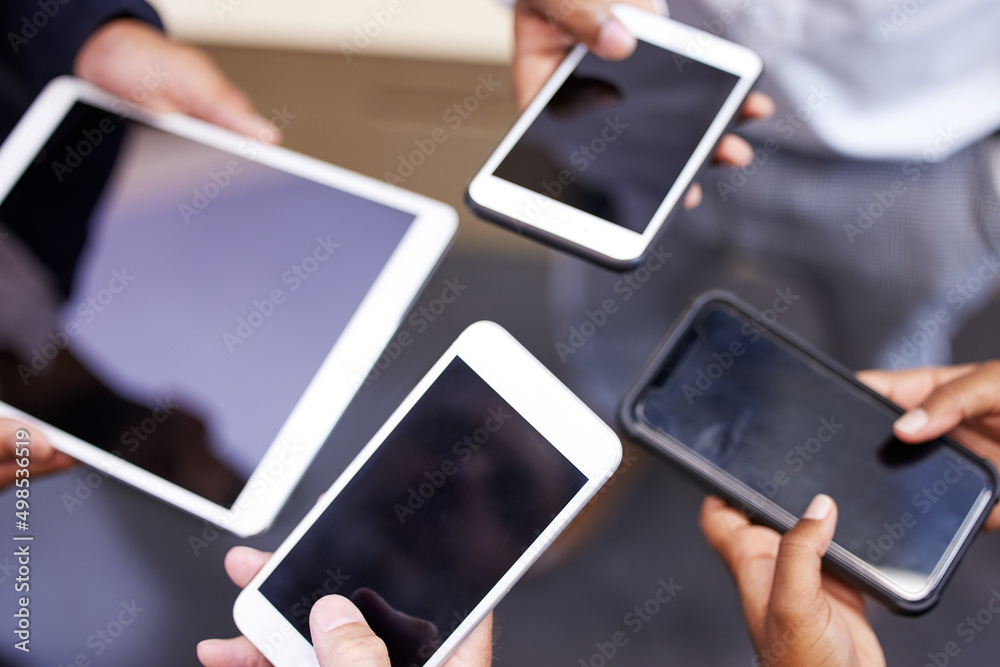 Poster Technology enables better communication among teams. Cropped shot of an unrecognizable group of businesspeople standing together in a circle and using technology.