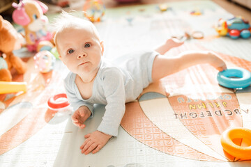 Portrait of wonderful baby girl laying on comfortable bed at home, adorable cute toddler look...