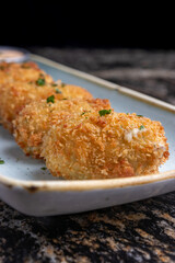 Croquetas crujientes de pescado sobe plato  con salsa. 