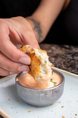 Manos de mujer cortando croqueta crujiente de pescado con salsa 