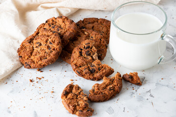 Oatmeal cookies with chocolate chips and a mug with milk on a light background. Breakfast concept.