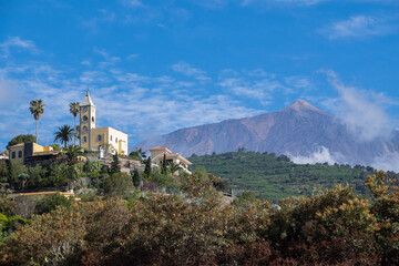 Fototapeta na wymiar Paisaje rural con vista de la Ermita de Nuestra Señora del Coromoto y del volcán Teide en la zona rural de La Guancha, en el norte de la isla de Tenerife, Canarias