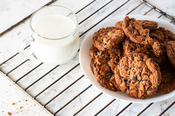 Oatmeal cookies with chocolate chips and a mug with milk on a light background. Breakfast concept.