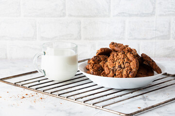 Oatmeal cookies with chocolate chips and a mug with milk on a light background. Breakfast concept.