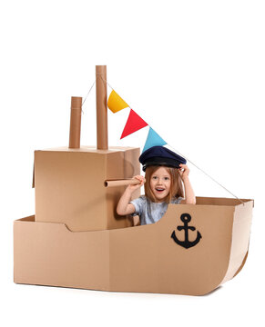 Cute little girl playing with cardboard ship on white background