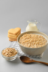 Bowl of healthy oatmeal with milk on light background