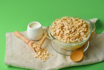 Bowl of healthy oatmeal on green background