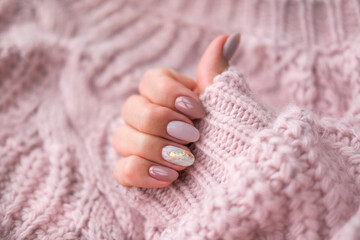 Women's hands with a beautiful  oval manicure in a warm pink knitted sweater. Winter trend, polish...
