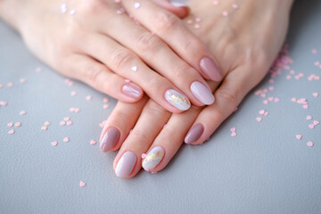 Women - hand with beautiful manicure  . Autumn trend, polish the beige and pattern on the nails...