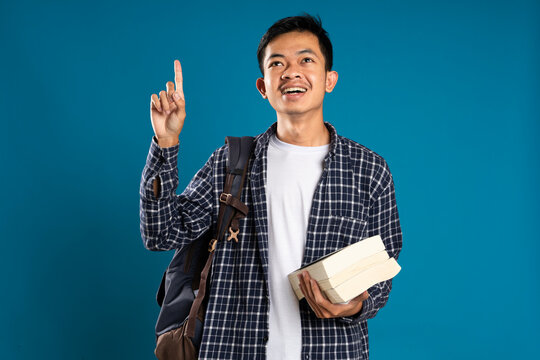 Content image of male student wearing shirt getting hand gesture idea while holding book isolated on blue background