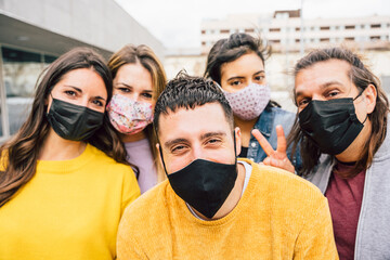 Portrait in the city of a group of friends smiling wearing protective face mask against Coronavirus infections, Covid-19 - Concept of unity and friendship
