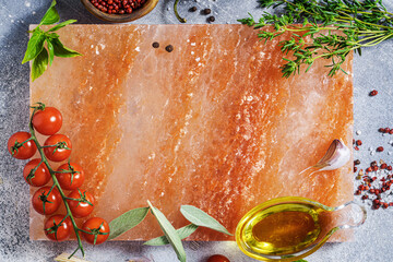 Food background with copy space. Pink himalayan salt block for cooking and serving and herbs and...