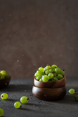 Ripe green gooseberries in a wooden bowl on a dark background. Harvest concept. Vegetarian food. Side view, copy space. Gardening
