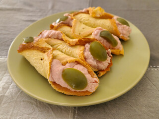 Cannoli salati ripieni di mousse alla ricotta e prosciutto cotto con olive verdi serviti come...